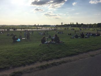 People on field against cloudy sky