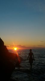 Silhouette man on beach against sky during sunset