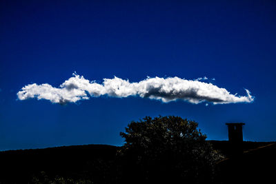 Low angle view of silhouette trees against blue sky