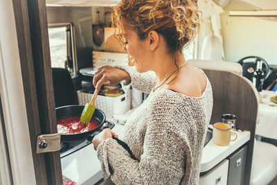 Side view of woman cooking in camper van