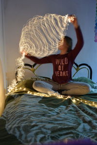 Rear view of woman sitting on bed