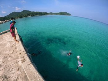 Boys looking at friends swimming in sea
