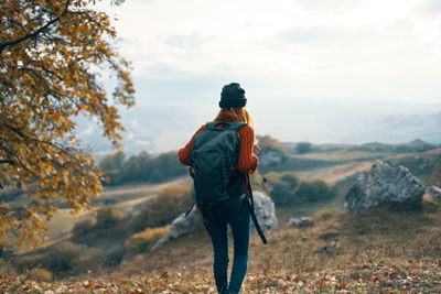 Rear view of man walking on mountain against sky