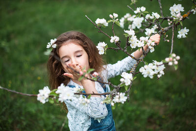 Portrait of smiling young woman blowing flowers