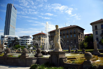 Statue by historic building against sky in city