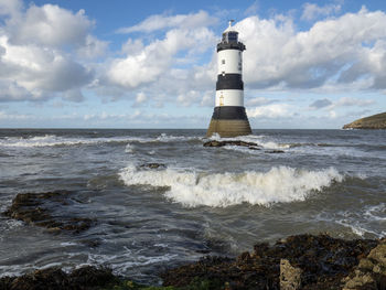 Lighthouse on beach against sky