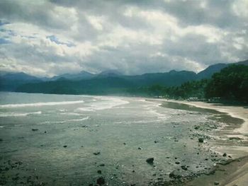 Scenic view of beach against cloudy sky