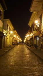 Illuminated street amidst buildings at night