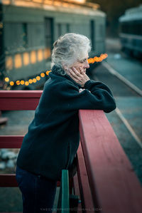 Side view of woman standing against built structure