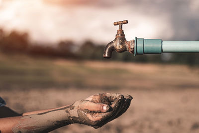 Close-up of hand holding faucet against blurred background