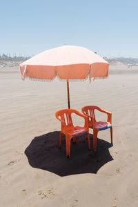 Deck chairs on beach against clear sky