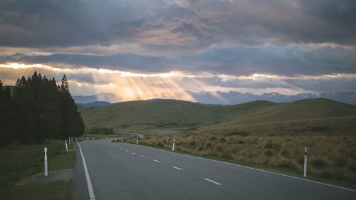 Road by mountains against dramatic sky