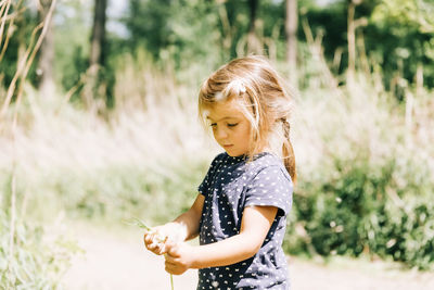 Cute girl holding plant standing outdoors