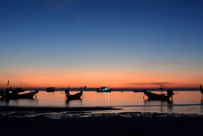 Silhouette boats in sea against sky during sunset