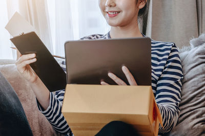 Young woman using laptop while sitting on sofa at home