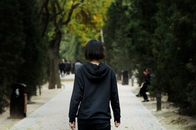 Rear view of woman walking against trees