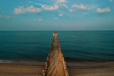 Diminishing perspective of pier over sea against sky during sunset