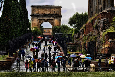 Tourists walking at arch of titus during rainy season