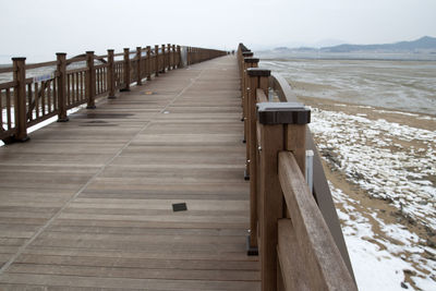 Wooden pier on beach against sky