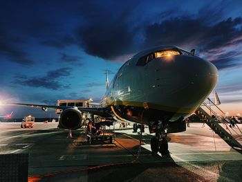 Airplane on airport runway against sky at dusk