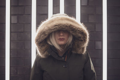 Woman in hooded clothing standing against illuminated lights