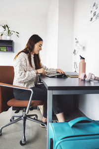 Young woman using laptop while sitting on table