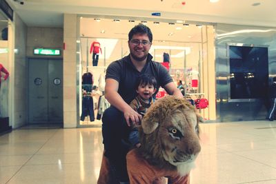 Portrait of smiling father and son playing at mall