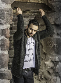 Midsection of man with text on brick wall