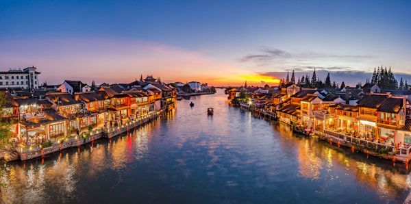 Panoramic view of sea and buildings against sky at sunset