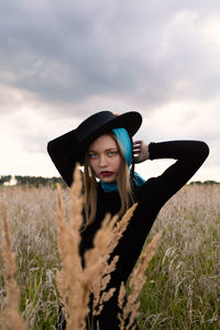 Portrait of beautiful woman standing on field against sky