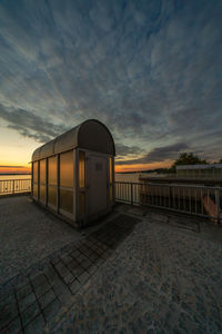 Built structure on beach against sky at sunset