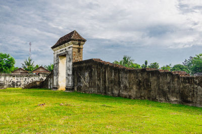 Old building on field against cloudy sky