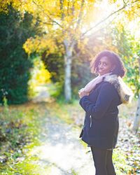 Full length of woman standing by tree during autumn