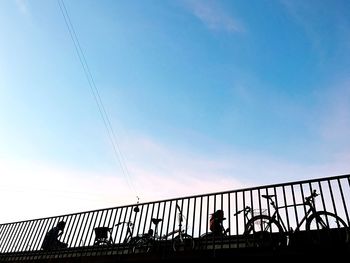 Low angle view of silhouette people on bridge against sky