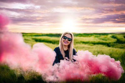 Smiling woman in wheat field at sunset