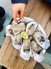 Cropped hand garnishing oysters on table