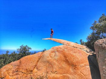 Low angle view of man on rock against sky