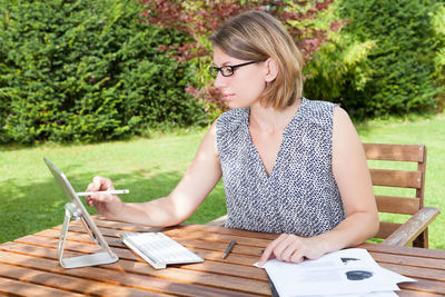 Young woman using smart phone while sitting on table