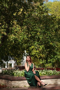 Young woman sitting against tree at park