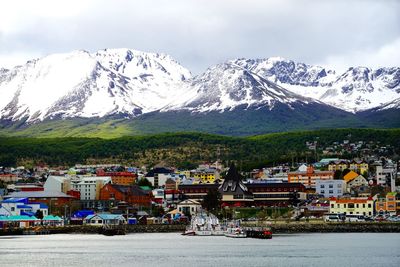 City by sea against snowcapped mountains