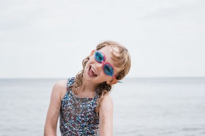 Young girl laughing with her goggles on whilst playing at the beach