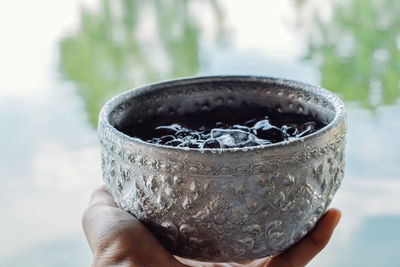 Cropped hand holding bowl outdoors