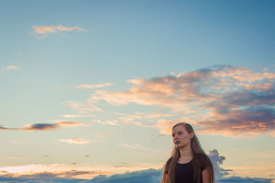 Portrait of beautiful young woman standing against sky