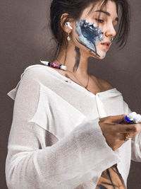 Close-up of woman with face paint against wall
