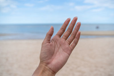Cropped image of person hand against sea