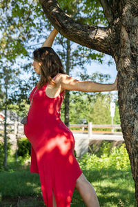 Full length of woman standing by tree trunk