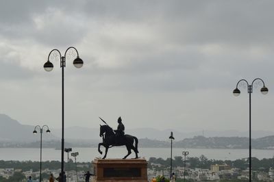 Statue on street against sky