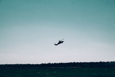 Silhouette airplane flying over field against sky