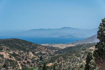 Scenic view of sea and mountains against clear blue sky