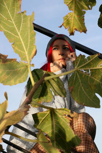 Low angle view of young woman standing against plants